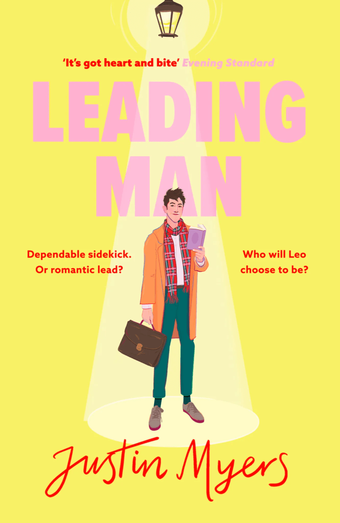 Cover image of Leading Man by Justin Myers. On a yellow background, standing beneath a spotlight, is a man. He is tall, and lanky, with thick, curling dark hair. He is white, with a slightly ruddy complexion, and wears brown-grey shoes, green trousers, a white shirt, a red tartan scarf, and an orangey-camel coloured coat. In one hand he holds a leather, flap-front briefcase, and in the other he holds a lilac book. Above the man, in a clear, bold sans serif font the title of the book [Leading Man] is written in bubblegum pink. Beneath the man, at the bottom of the page, the author's name [Justin Myers] is written in a red handwriting font.